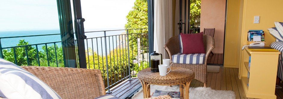 Sunny lounge area at The Haven with open doors leading to a balcony and ocean views