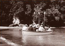Historic photograph of a rowboat approaching the beach with bush behind
